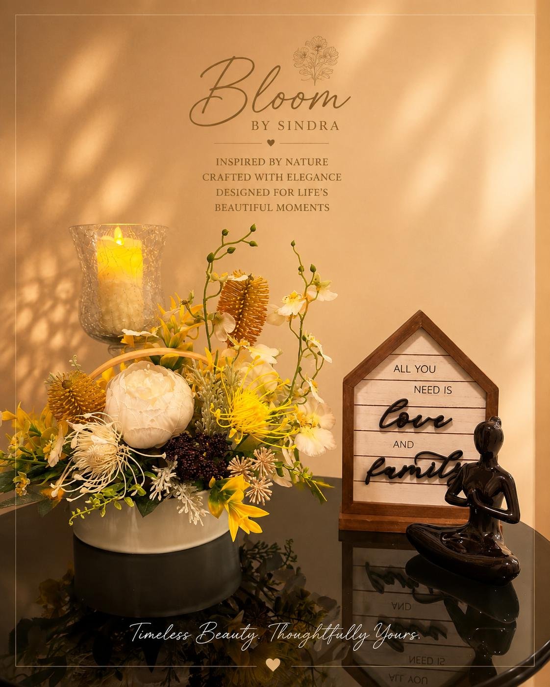 Bloom by Sindra branded photo of a yellow and white arrangement styled beside a Love and Family sign and meditating figurine